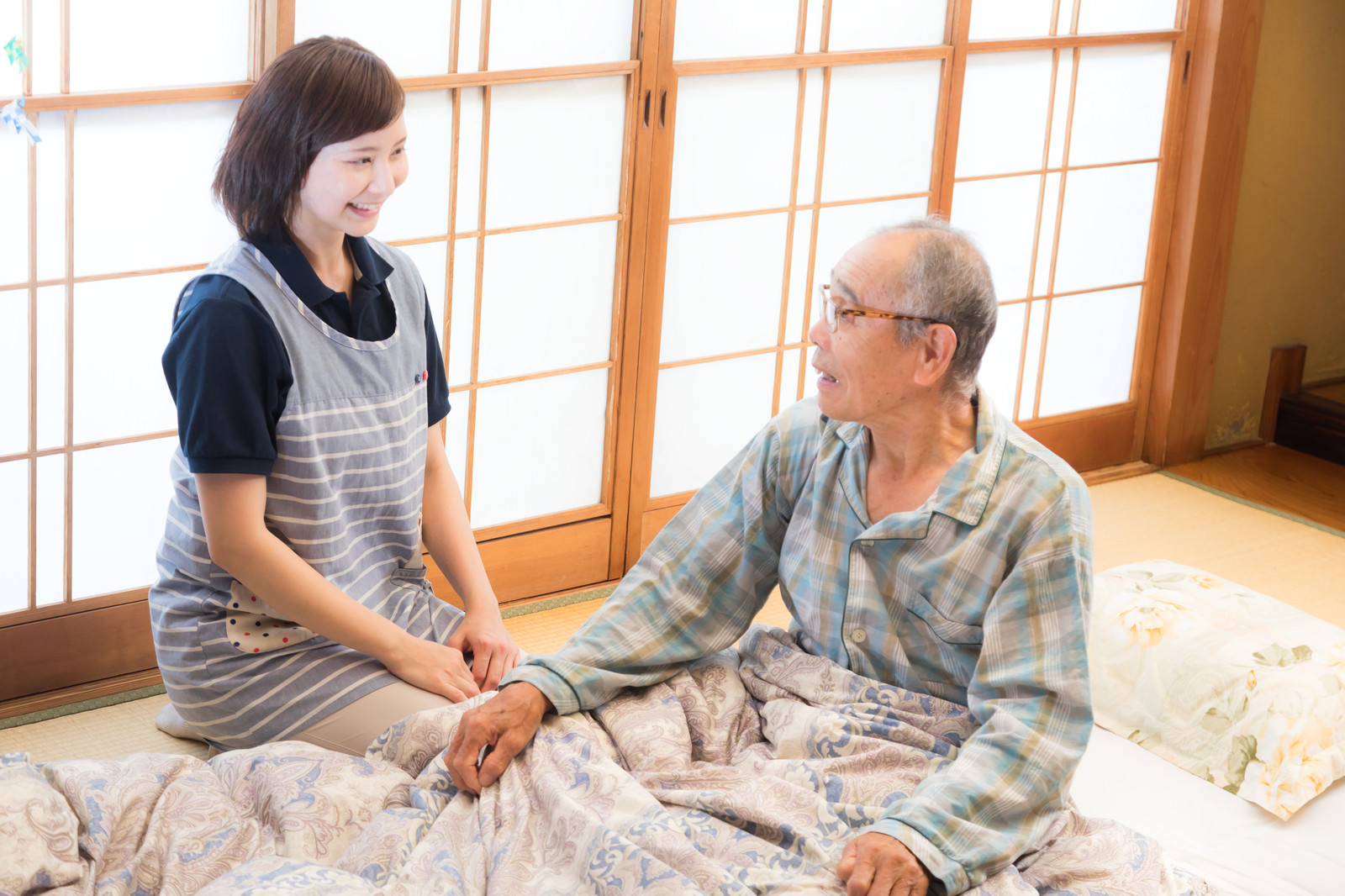 布団のそばで利用者と会話するてとてケアのスタッフ
